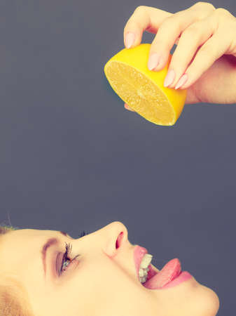 Healthy diet, refreshing food full of vitamins. Woman drinking juice from juicy fruit, yellow lemonの写真素材