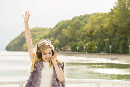 Happy joyful woman listening to music while being outdoor. Teenage female wearing headphones having fun on a walk.の写真素材