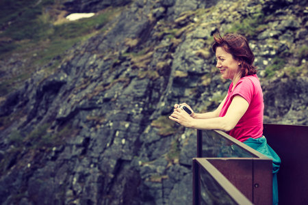 Travel, beauty in nature. Tourist woman looking at mountains, taking picture with camera from...