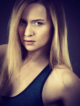 Beautiful young woman having serious nervous face expression looking scary. Dark background.の写真素材