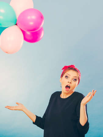 Craziness and lots of fun. Cute crazy joyful girl playing with colored balloons. Blonde playful retro style woman feel craze.の写真素材