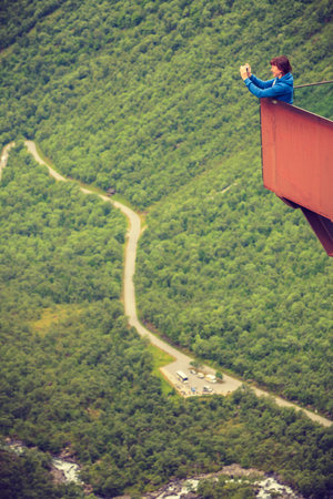 Travel concept. Tourist woman looking at Trolls Path Trollstigen or Trollstigveien winding scenic...