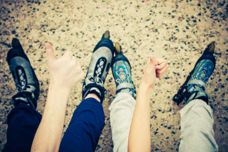 People friends with roller skates giving thumb up gesture. Woman and man relaxing outdoor.の写真素材