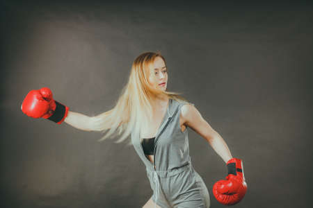Young sensual woman, blonde attractive girl wearing red punch boxing gloves. Sport fitness and power concept.の写真素材