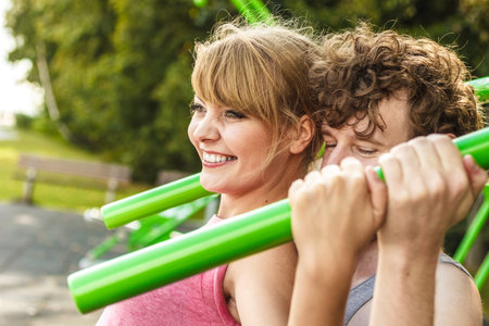 Active young man and woman exercising on pulldown machine. Muscular strong guy and girl in training...