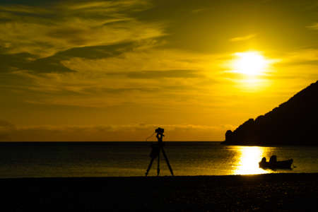 Professional camera taking picture film video of scenic orange sunrise or sunset over sea surface, Greece Peloponnese.の写真素材