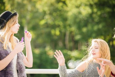 Vacations joy, friendship concept. Women friends having fun blowing soap bubbles outdoor.の写真素材