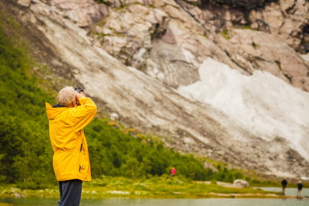 Tourism vacation and travel. Male tourist taking photo with camera, enjoying mountains landscape,...