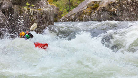 Scandinavian sports concept. People doing extreme white water mountain canoeing in rough river.の写真素材