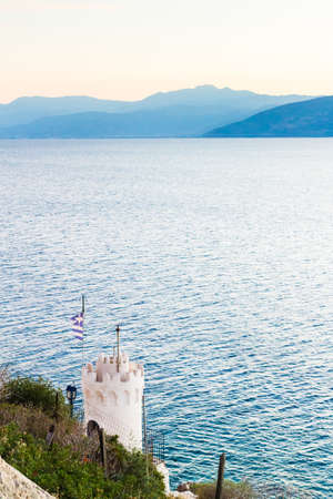 Little church with greek flag on rocky seashore near Karathonas beach.の写真素材