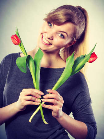 Happiness and satisfaction with life. Blonde woman wearing eyewear with single red green tulip. Happy joy girl feeling spring time holding beautiful flower.の写真素材