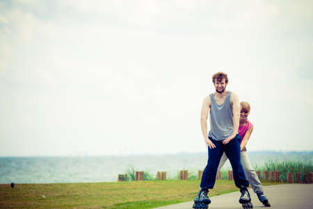 Active lifestyle people and freedom concept. Young fit couple on roller skates riding outdoors on sea coast, woman and man enjoying time together.の写真素材