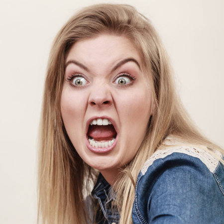Angry furious blonde woman screaming and yelling at somebody having funny crazy face expression.の写真素材