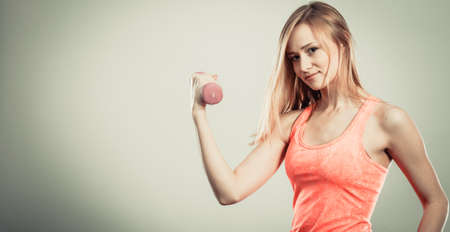 Bodybuilding. Strong fit woman exercising with dumbbells. Muscular blonde girl lifting weights studio shotの写真素材