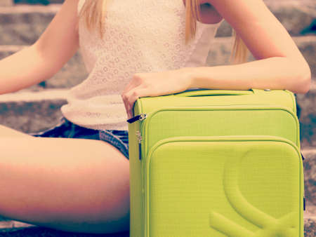 Travel and journey. Part body of female tourist traveller. Girl with green luggage suitcase baggage travelling visiting.の写真素材