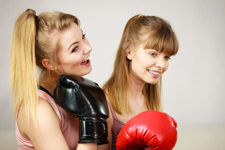 Friendship, human relations concept. Two happy women friends having fun smiling with joy wearing boxing gloves being fit and sporty.の写真素材