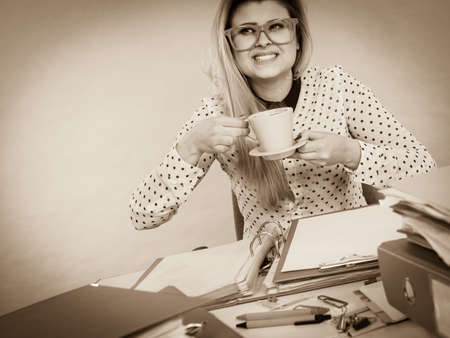 Happy woman at office drinking hot coffee or tea enjoying her break time during work. Job relax.の写真素材