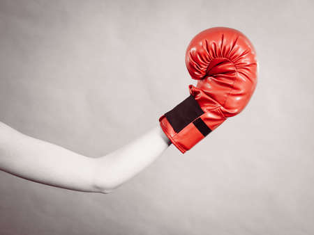 Unrecognizable sporty woman holding red boxing gloves. Studio shot on grey background.の写真素材