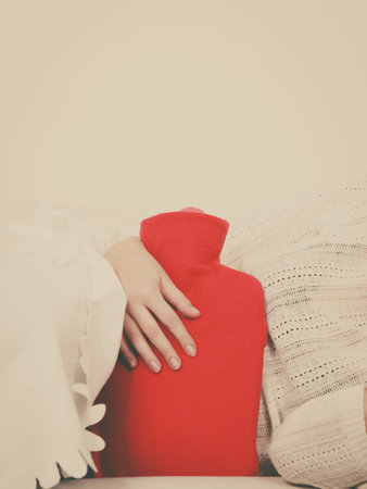 Painful periods and menstrual cramp problems concept. Woman feeling stomach cramps lying on cofa...