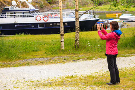 Tourist adult woman taking picture using professional camera. Photographing norway landscapes.の写真素材