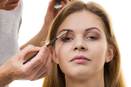 Young woman getting her eyebrow make up done by professional visage artist. Person using brush to paint eyebrows.の写真素材