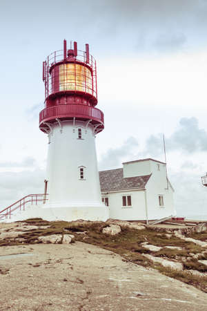 Historic red white lighthouse on the edge of rocky sea coast, South Norway, Lindesnes Fyr beaconの写真素材