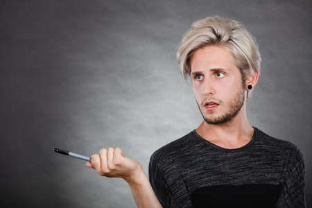 Young man confused thinking seeks a solution. Decision making process, doubt concept, studio shot on dark.の写真素材