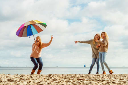 Three women full of joy having great time together. One woman holding colorful umbrella.の写真素材