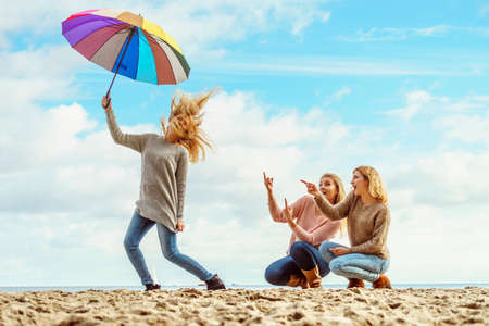 Three women full of joy having great time together. One woman holding colorful umbrella.の写真素材