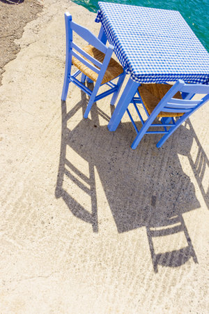 Seaside blue table and chairs open cafe outdoor restaurant in Greece on sea shore. Summer vacation...
