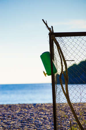 Small growing plant secured with fence and rocks stones on sandy beachの写真素材