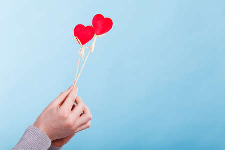 Romance valentines relationship affection concept. Person holding two hearts. Hands with two love symbols on poles.の写真素材