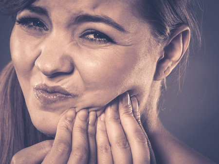 Dental care and toothache. Young woman achy girl suffering from terrible tooth pain, touching...