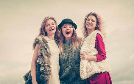 Three fashionable women having presenting pretty stylish outfits. Style, fashion, friendship concept.の写真素材