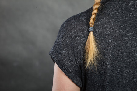 Hairstyles and hairstyiling concept. Woman with dark blonde hair and braid hairdo, back view. Studio...