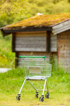 Random shopping cart trolley in nature. Norwegian green background landscape. Tourism, buying concept.の写真素材