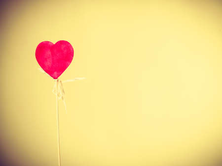 Valentines Day. Male hand holding showing red little heart on stick. Man presents palm with love sign symbol.の写真素材