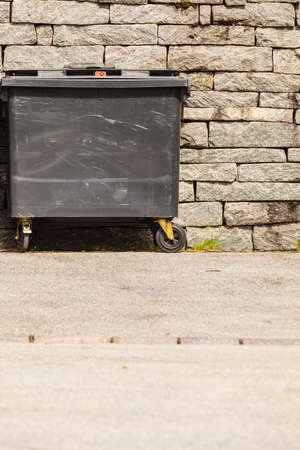 Rubbish recycling concept. Black industrial trash cay on wheels, dumpster containers, littler garbageの写真素材