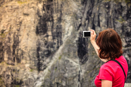 Travel, beauty in nature. Tourist woman looking at mountains, taking picture with camera from...
