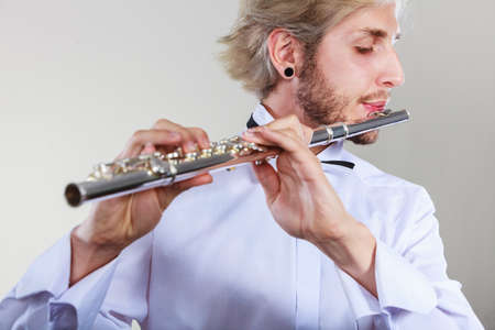 Flute music playing professional male flutist musician performer. Young elegant stylish man with instrumentの写真素材