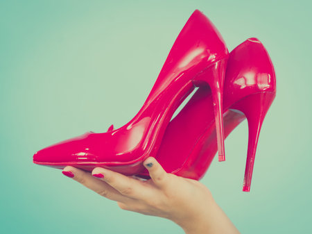 Woman hand fashion stylist presenting her elegant shoes. Beautiful red sensual high heels. Outfit accessoriesの写真素材