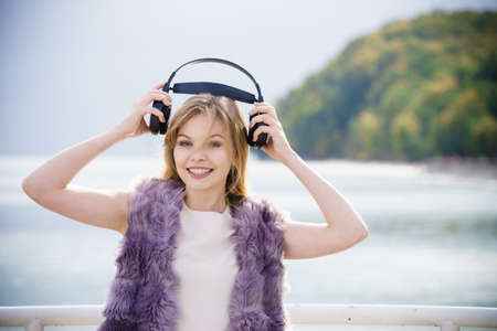 Happy joyful woman listening to music while being outdoor. Teenage female wearing headphones having fun on a walk.の写真素材