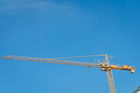 Construction site building hoisting crane on evening clear blue sky background. Industrial object concept.の写真素材