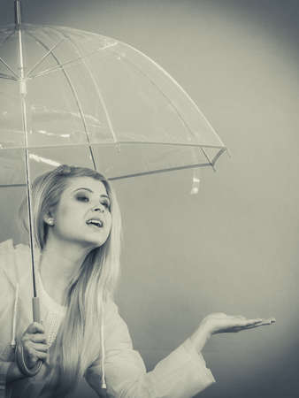 Woman wearing raincoat holding transparent umbrella checking weather if it is raining.の写真素材