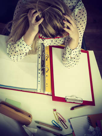 Mobbing at work, bad job relations concept. Depressed businesswoman being sad and tired sitting working at desk full off documents in binders.の写真素材