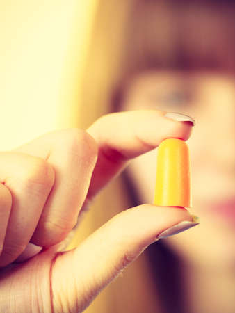 Woman holding protective ear plugs. Getting rid on noise in loud place, hearing protection concept.の写真素材