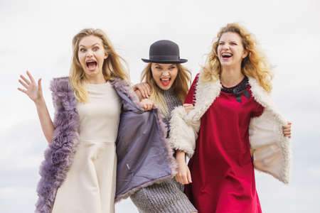 Three fashionable women having presenting pretty stylish outfits. Style, fashion, friendship concept.の写真素材