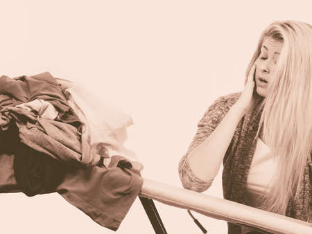 Household duties, domestic chores concept. Shocked woman holding iron about to do ironingの写真素材