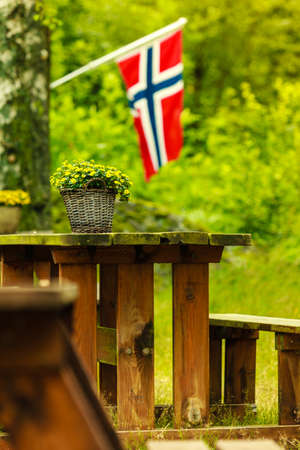 Norwegian flag and picnic site wooden table and benches outdoor in green forest park, Europe.の写真素材
