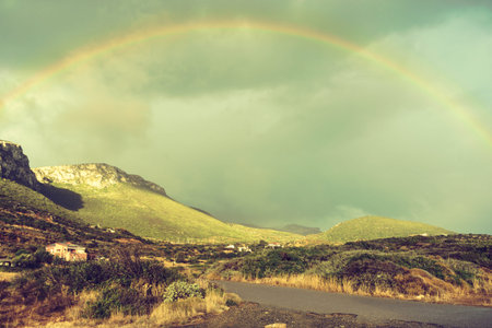 Beautiful rainbow on dark sky with clouds after rain. Weather forecasting, beauty in nature concept.